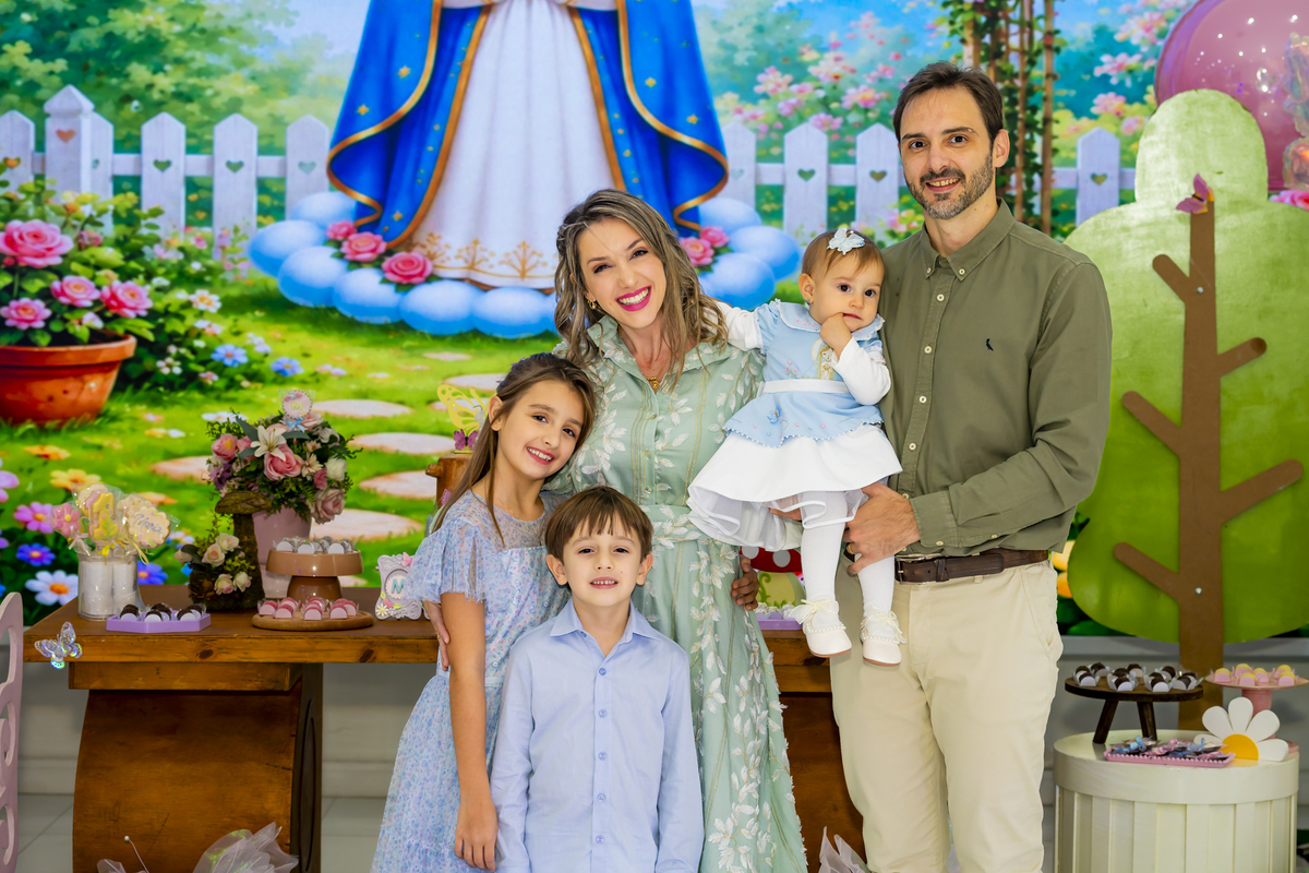 Retrato de família completa posando diante da decoração temática de jardim na festa de aniversário.
