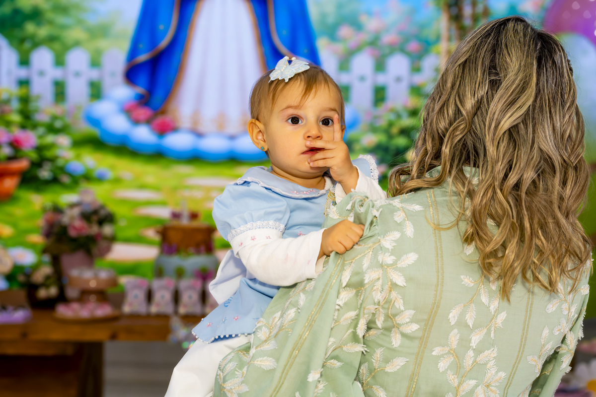A aniversariante nos braços da mãe, momento carinhoso durante a celebração de 1 ano.