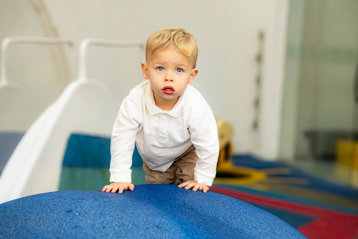 Menino explora brinquedo de escalada na área kids do buffet Lá Vem o Sol - Lua, em Alphaville. Roupa branca e cenário lúdico reforçam o clima de diversão da festa de aniversário.