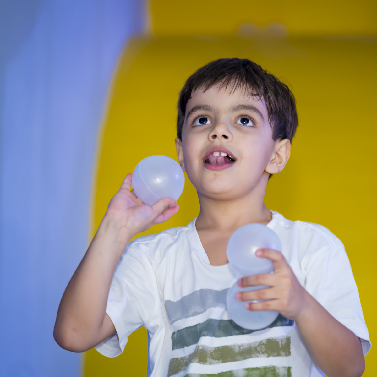 Criança brinca com bolinhas em ambiente colorido durante celebração de aniversário infantil.
