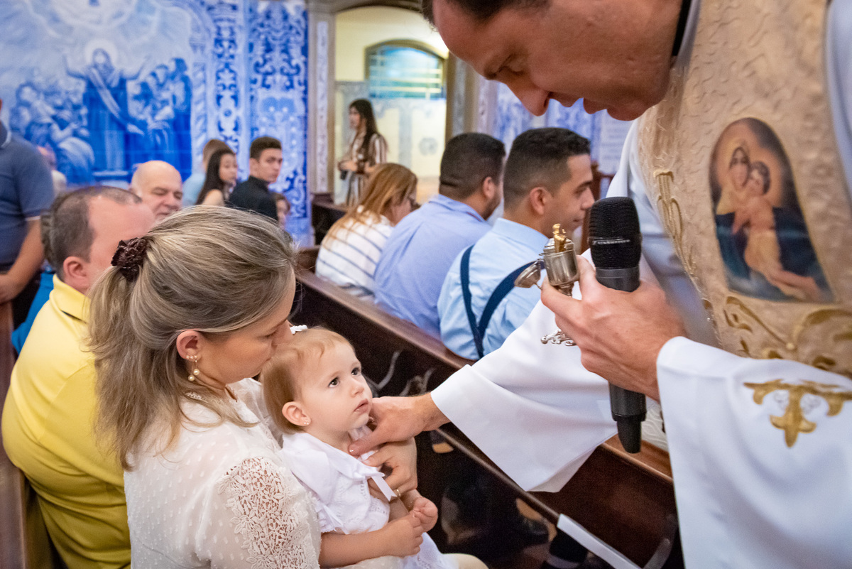 Fotografia de batizado na Igreja Nossa Senhora do Brasil. Foto  de batizado Padre ungindo o peito da criança em batismo na Igreja Nossa Senhora do Brasil - São Paulo
