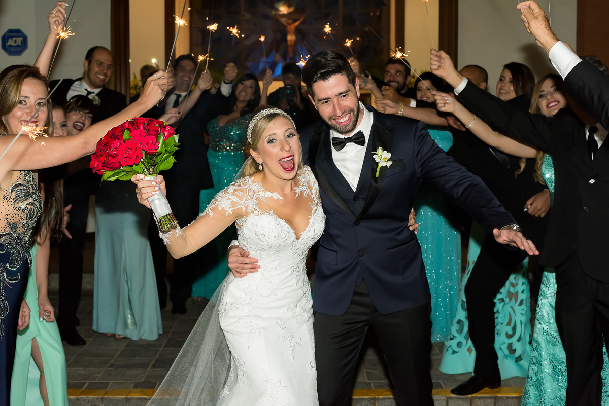 noivos saindo da igreja e passando pelos padrinhos