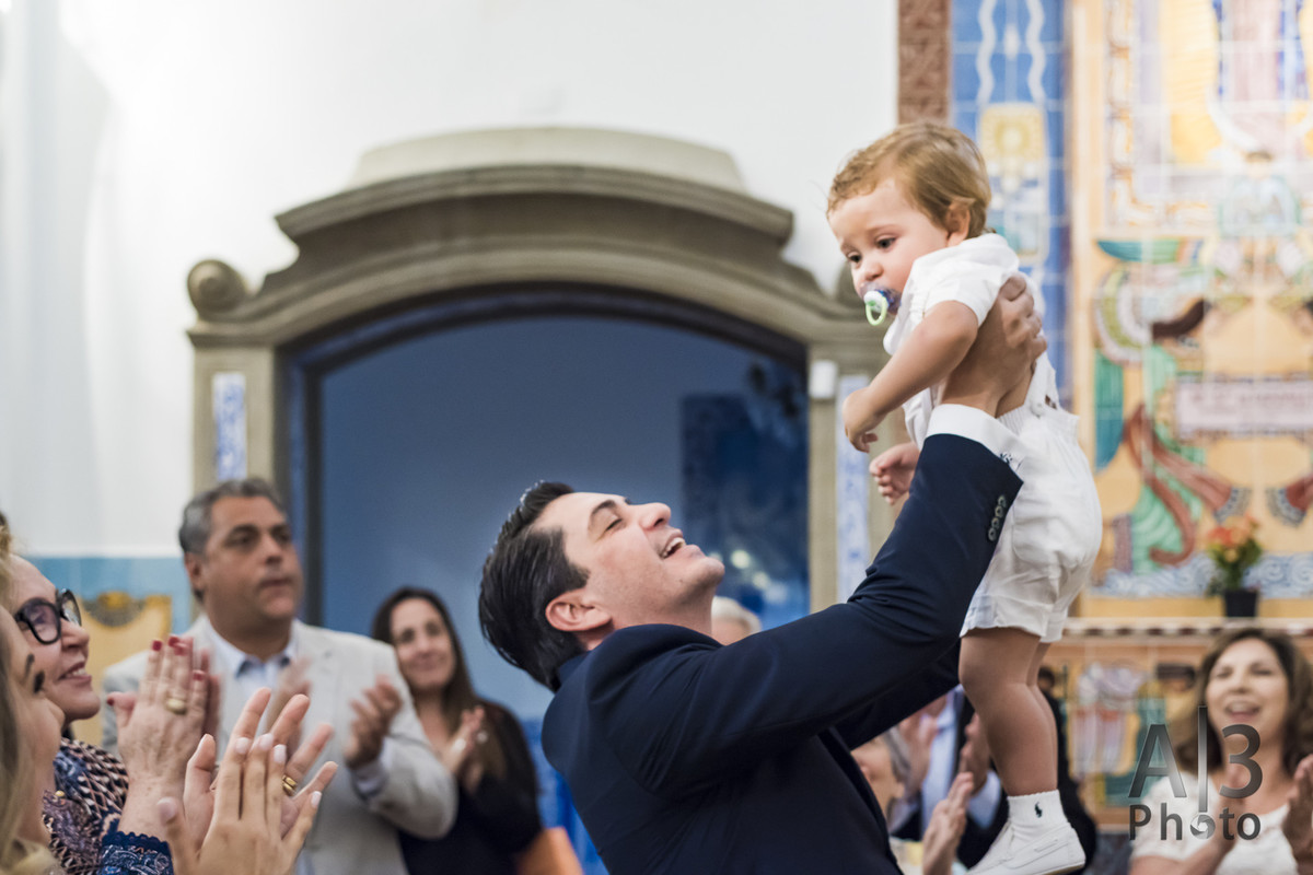 fotografia de batizado em são paulo. fotografia de batizado na igreja nossa senhora do brasil. pai levanta criança no dia do batizado