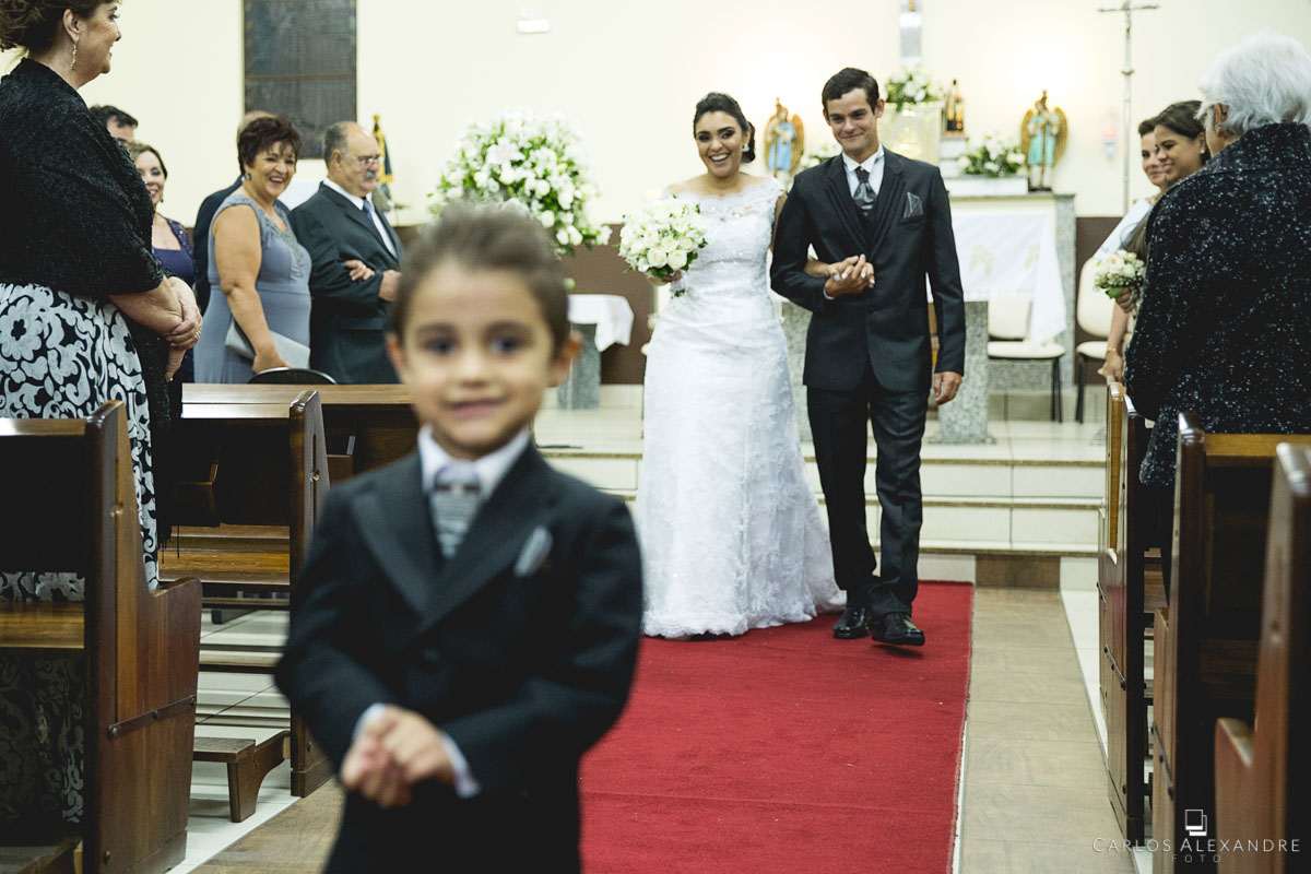 saída dos noivos com o pagem na frente roubando a cena no casamento fotografado em três corações MG, Sul de Minas pelo fotógrafo de casamentos Carlos Alexandre