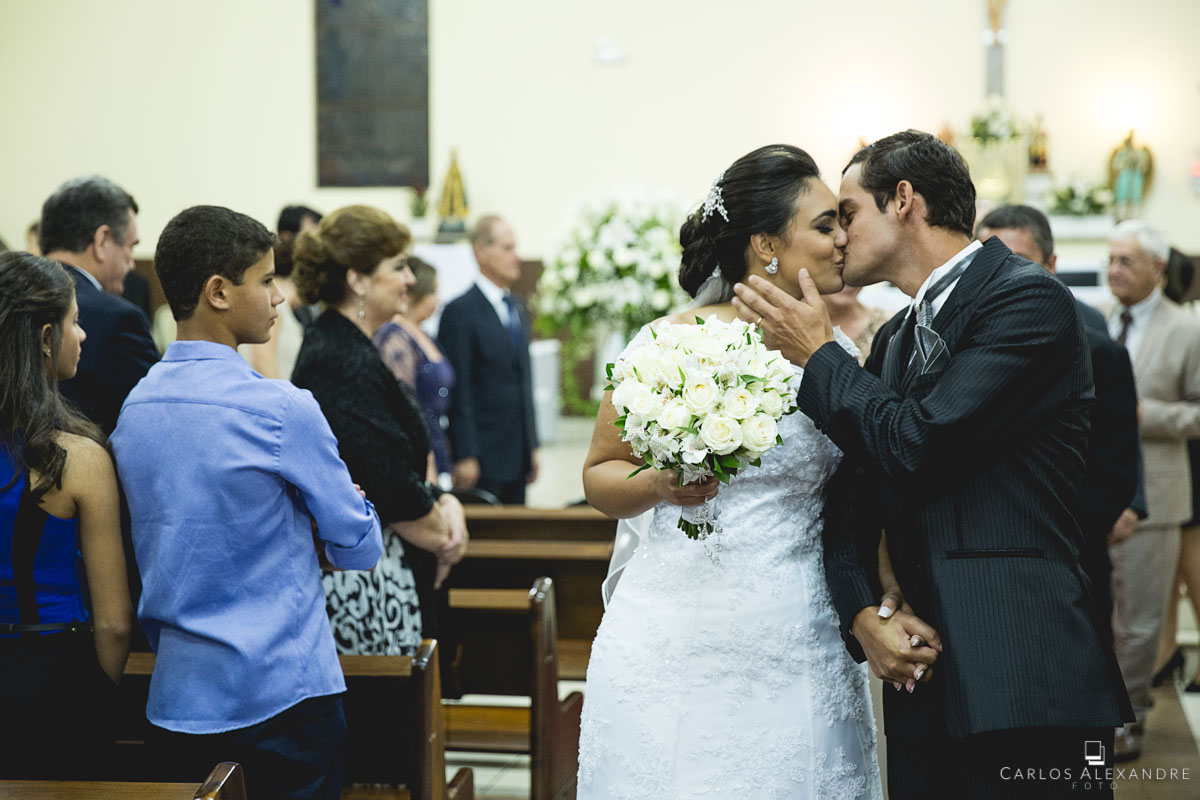 noivos se beijando na saída do casamento compartilhando a alegria em casar com os convidados
