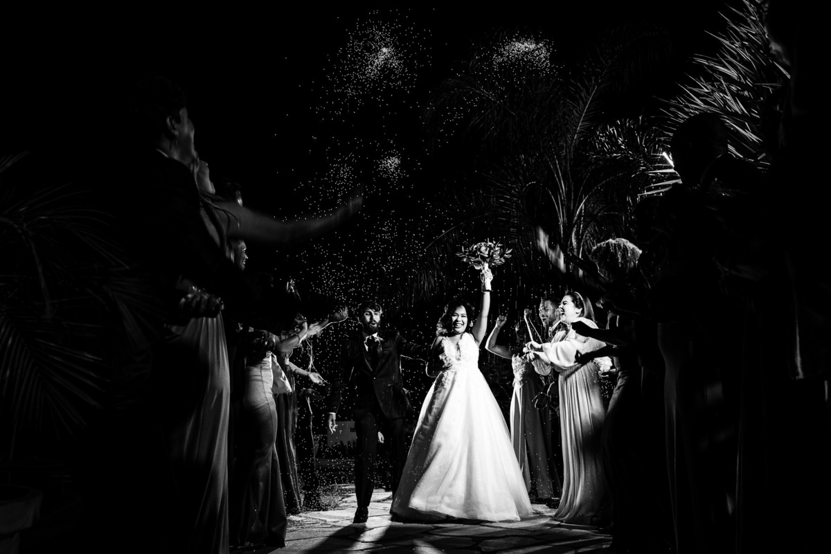 entrada dos noivos com os padrinhos jogando arroz no corredor festa na fazenda cachoeira três coracoes