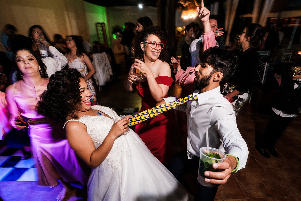 noiva puxando o seu noivo pela gravata de patinho na festa festa na fazenda cachoeira três coracoes