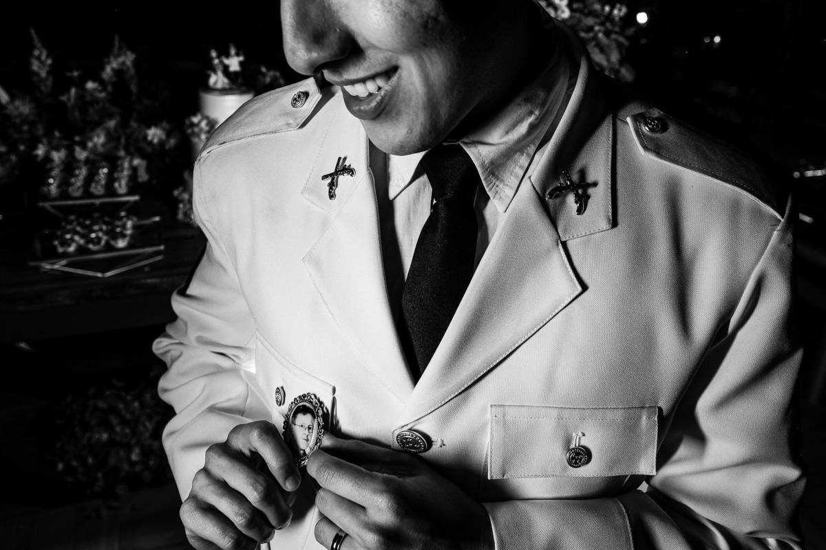 retrato do noivo arrumando o broche com a foto de seu pai