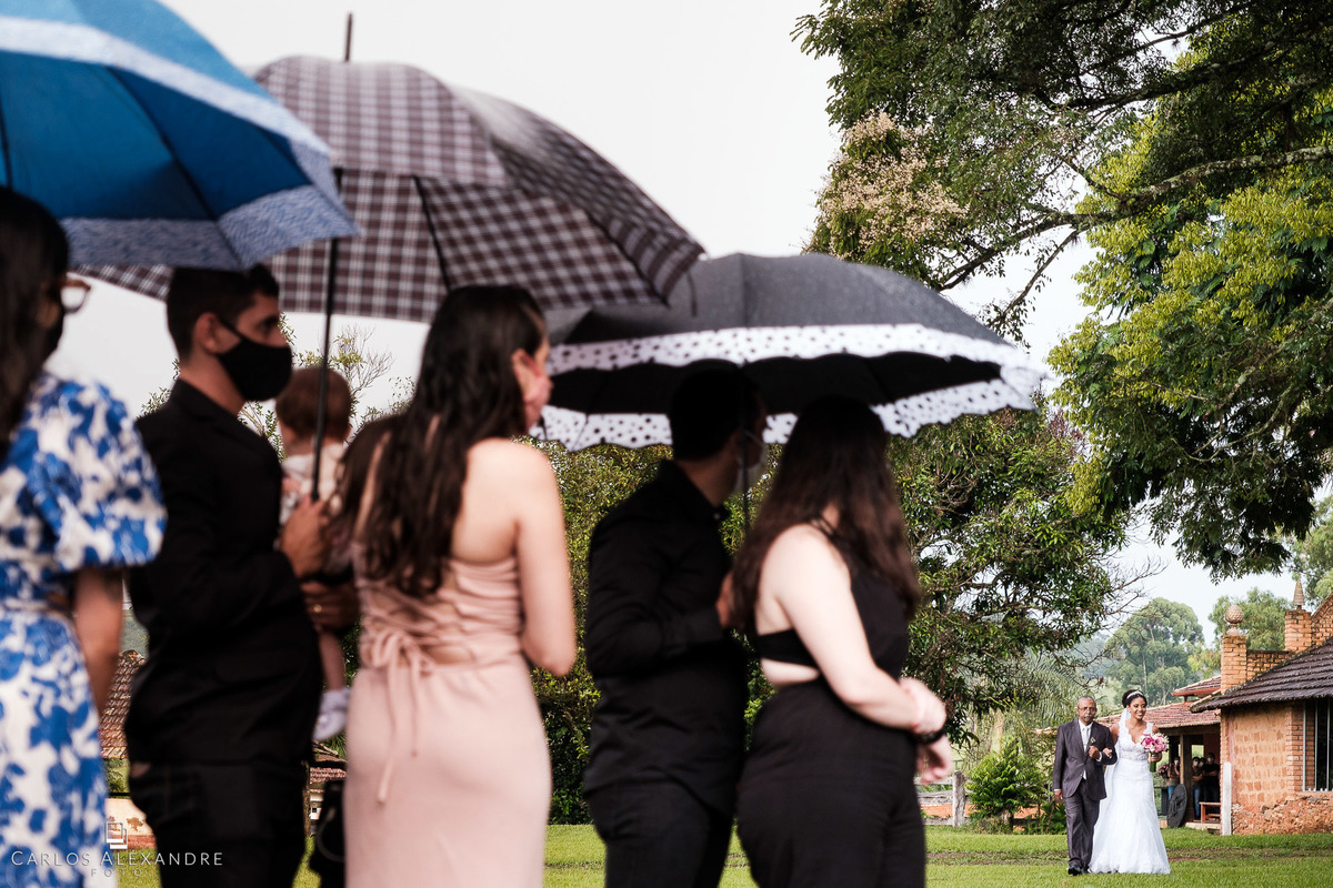 noiva entrado com seu pai em meio aos guarda chuvas com tempestade