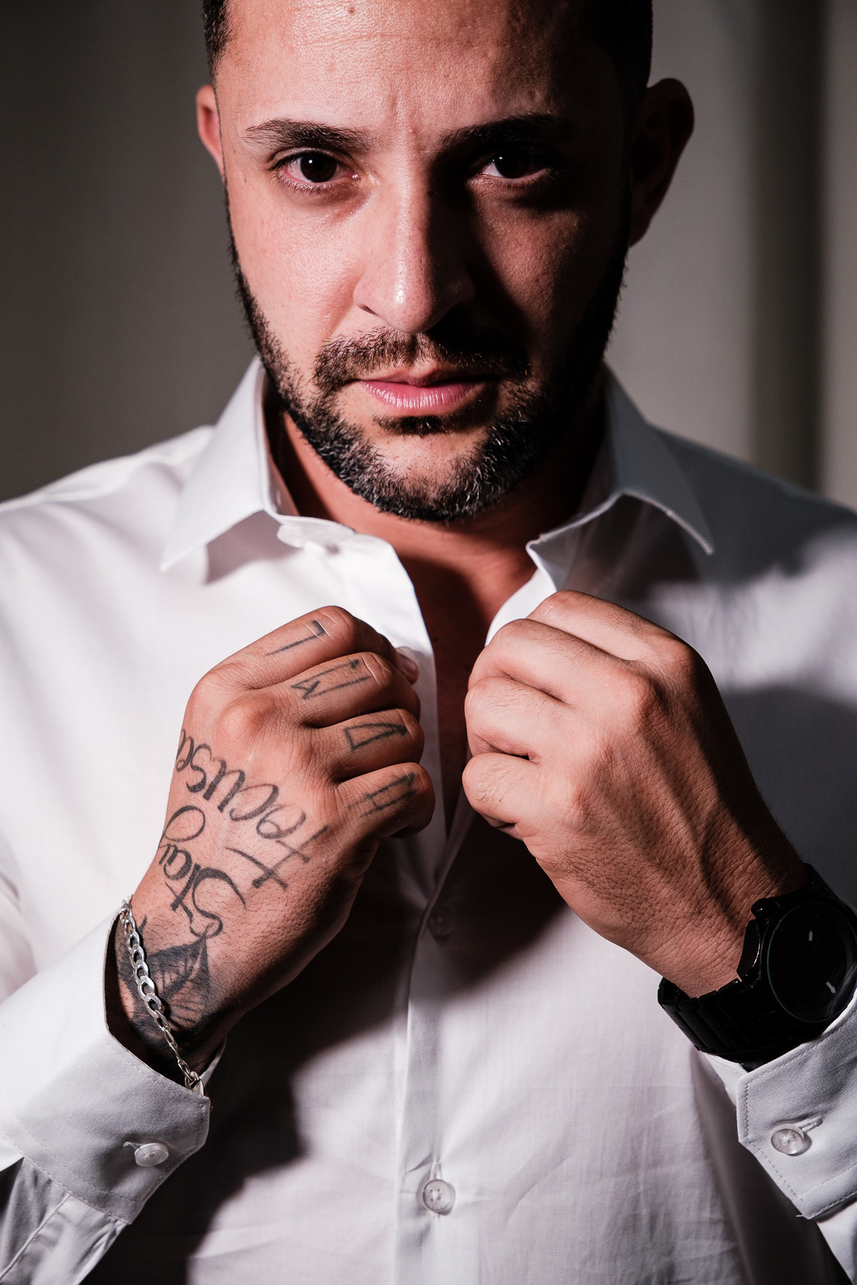 retrato do noivo fechando a camisa mostrando suas tatuagens na mão