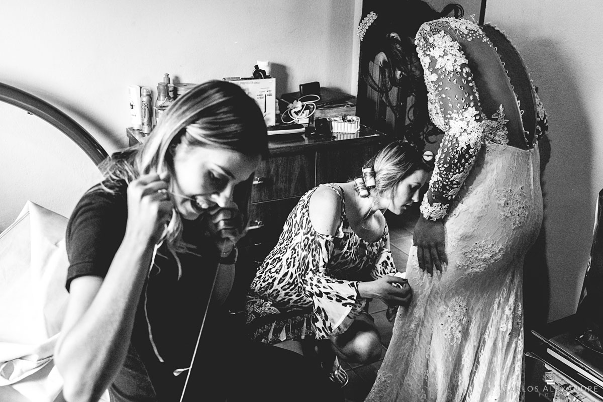 amigas e madrinhas arrumando o vestido da noiva antes de começar o casamento em seu making of na casa de sua avó fotografado por carlos alexandre foto fotógrafo em três corações sul de minas
