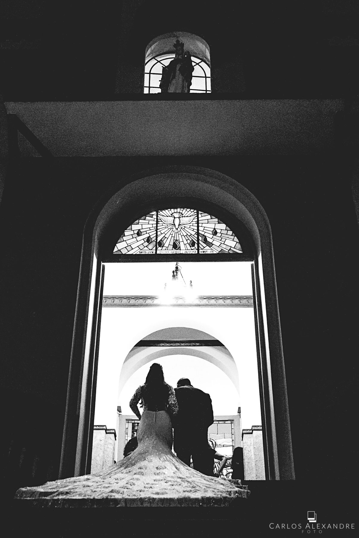noiva e seu pai entrando pela porta da igreja no grande momento da cerimônia fotografado por carlos alexandre foto fotógrafo em três corações sul de minas