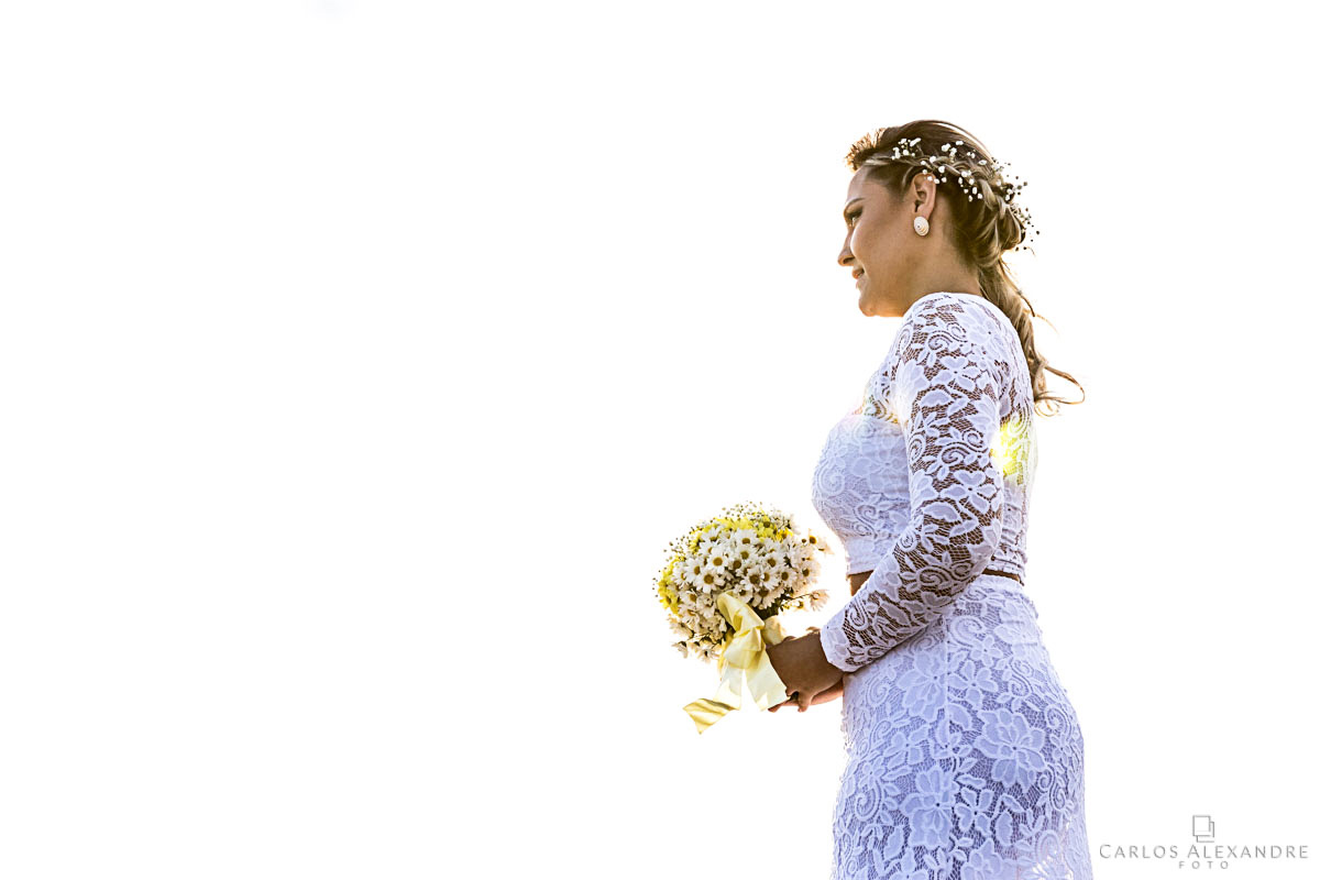 noiva toda de branco com o fundo todo branco segurando as lágrimas fotografo de casamento três corações mg carlos alexandre foto casamento em são thomé das letras sul de minas