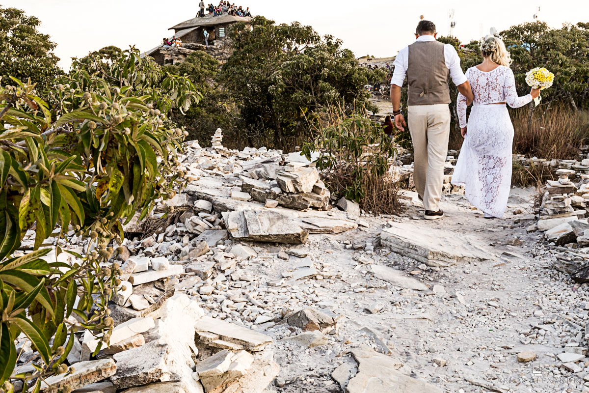 noivos caminhando rumo à pirâmide com pedras no caminho fotografo de casamento três corações mg carlos alexandre foto casamento em são thomé das letras sul de minas