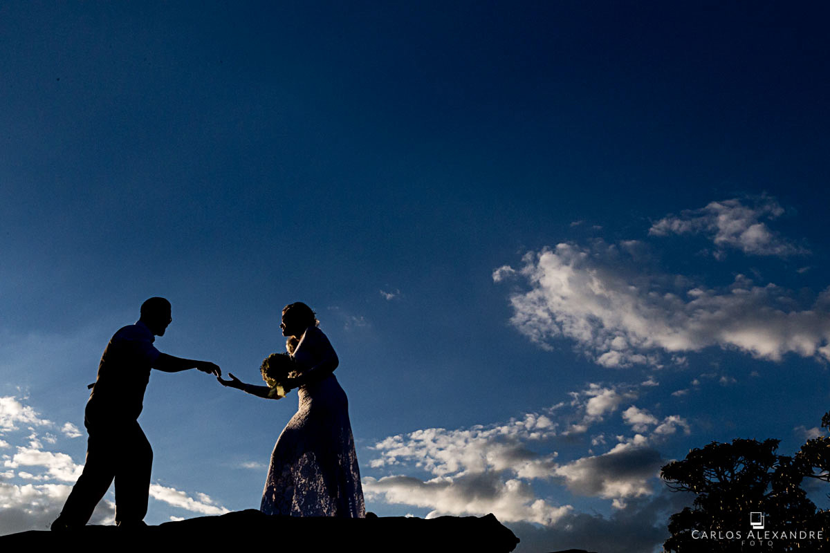 contra luz do casal com o fundo azul do ceu fotografo de casamento três corações mg carlos alexandre foto casamento em são thomé das letras sul de minas
