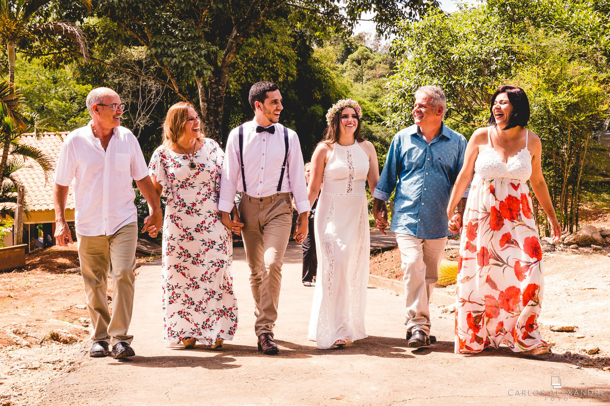 noivos e seus pais de mãos dadas dando gargalhadas casamento ao ao livre em varginha fotografado por carlos alexandre foto fotografo de casamento em três corações