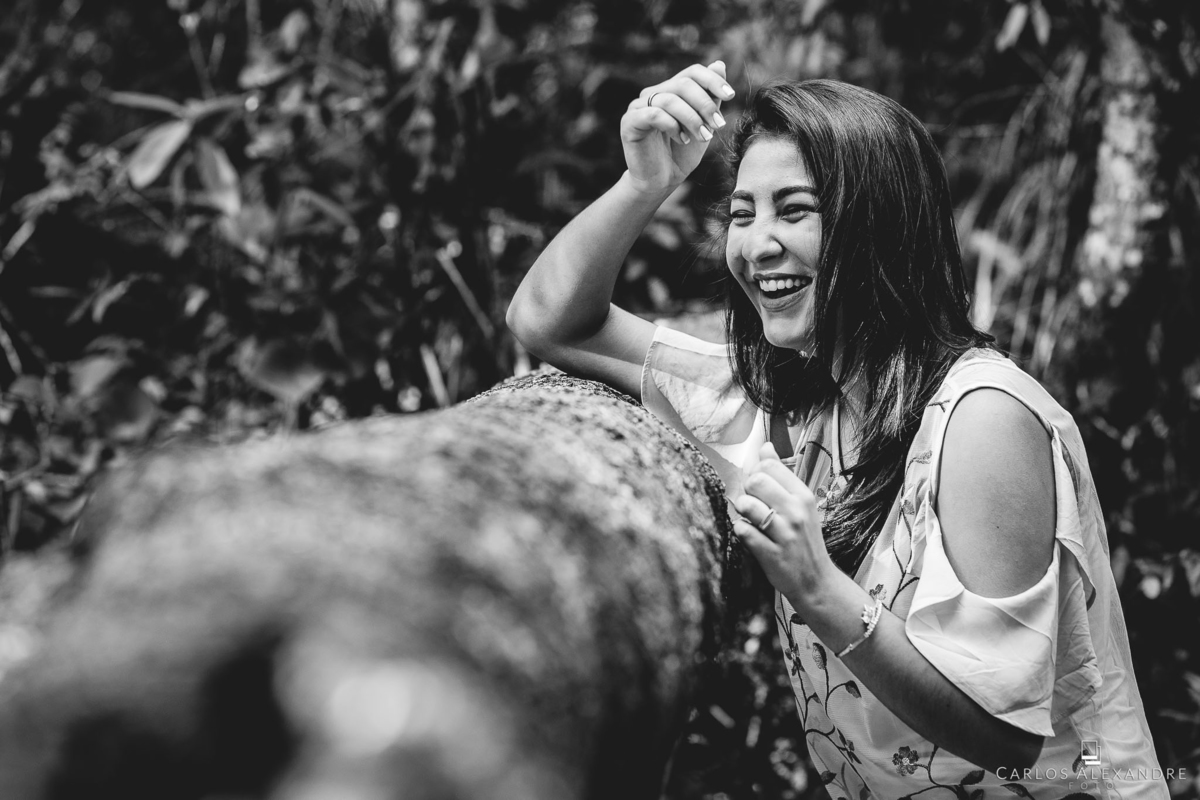 menina debruçada nos galhos do bosque dando gargalhadas gostosas