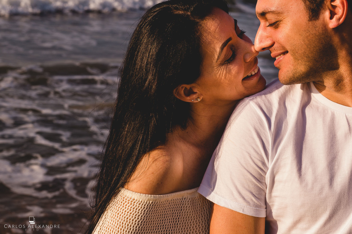fotografia do casal com mar ao fundo, à luz do dia do nascer do magnifico sol