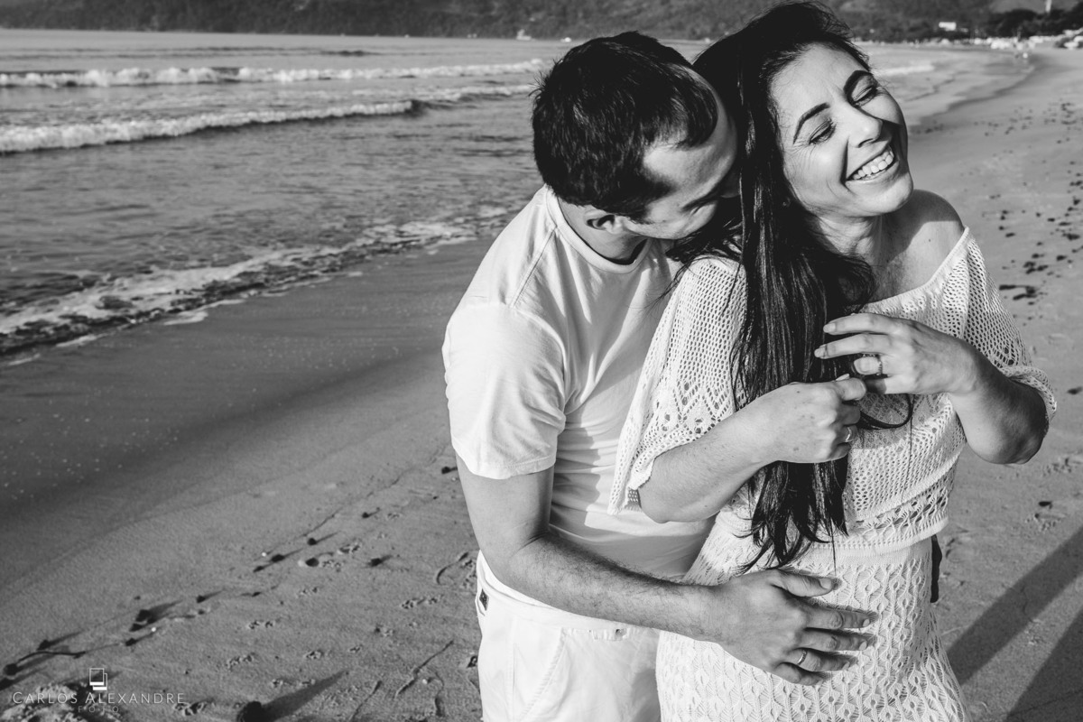 ensaio pré wedding em praia Ubatuba Sp fotografado por Carlos Alexandre Foto casal se agarrando em uma paixão linda de se ver. a namorada se entrega com um lindo sorriso