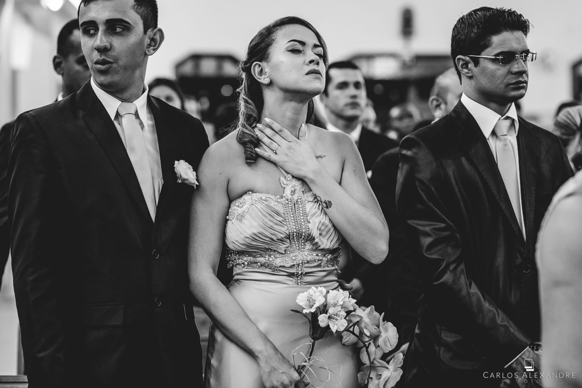 madrinha ora emocionada abençoando o seu casal de noivos, com a mão no peito conectada com Deus, fotógrafo de casamentos Carlos Alexandre Fotografia Três Corações MG