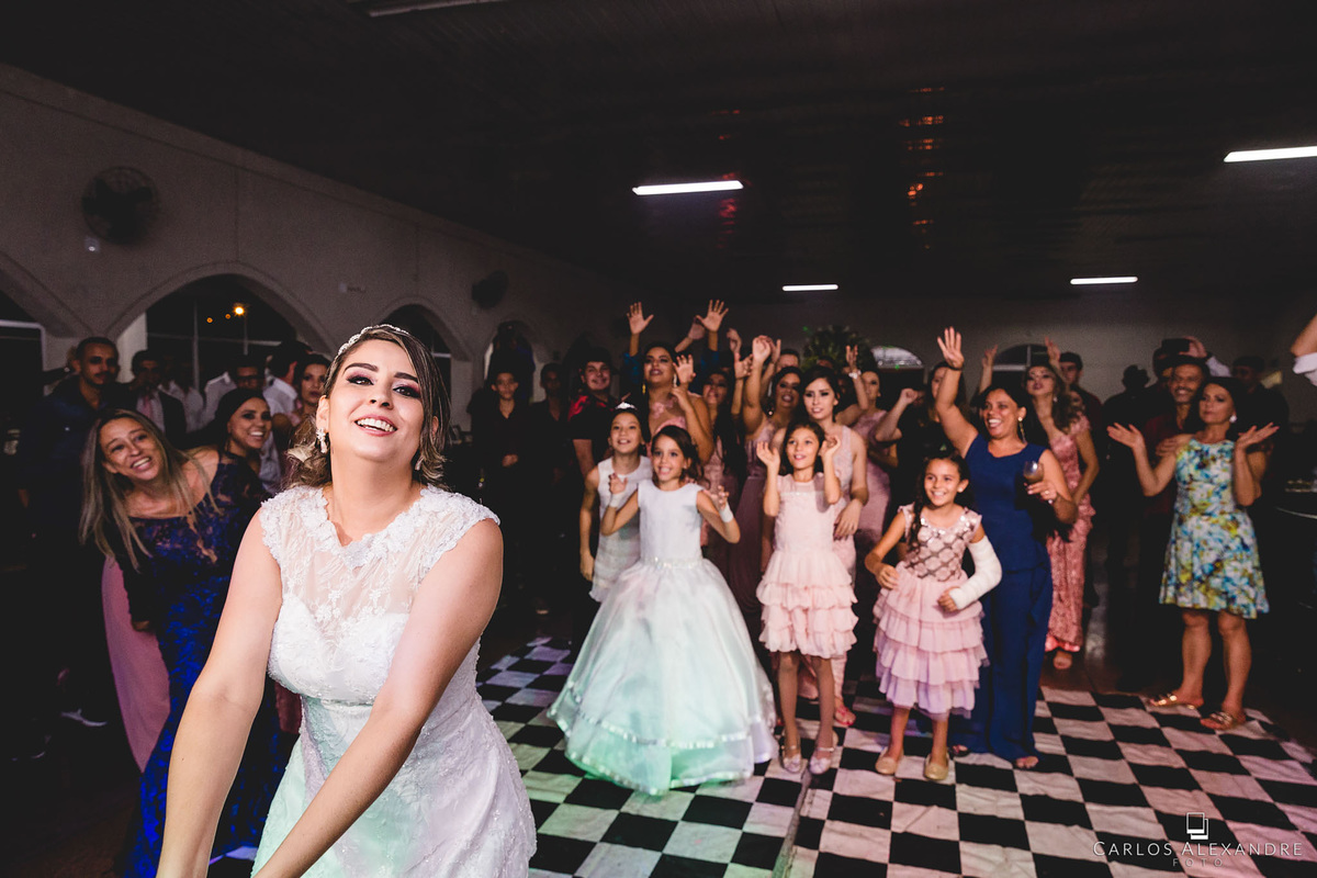 noiva ao jogar o buquê com as solteiras ao fundo, fotografado por carlos alexandre, da cidade de 3 corações, e sul de minas