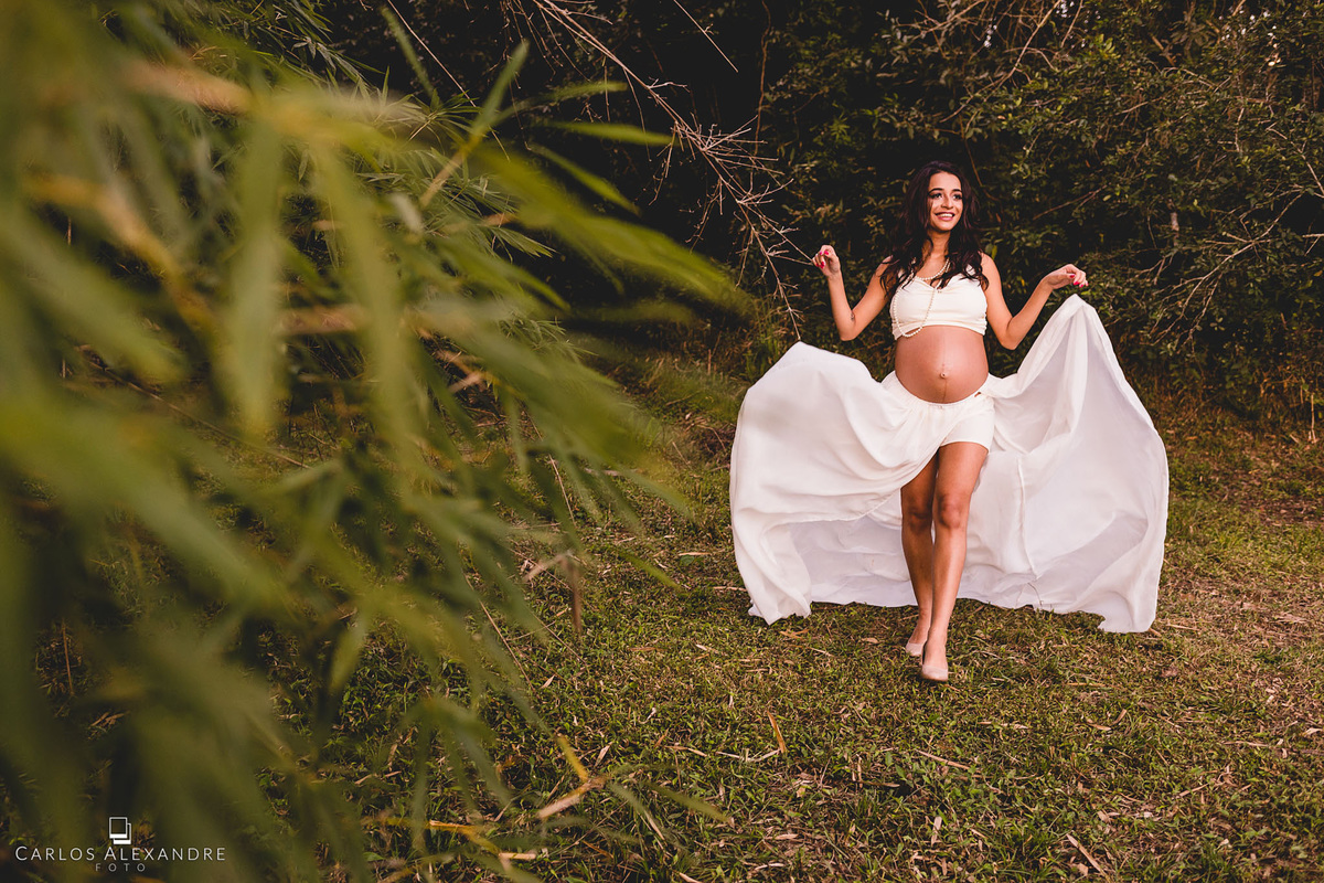 vestido com calda para gestante sendo jogado no ar enquanto mãe caminha, fotografia de grávida carlos alexandre foto tres coracoes sul de mg