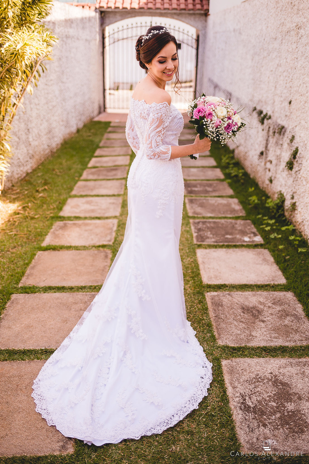 lindo vestido de noiva sendo mostrado de costas enquanto segura o buquê em seu making of, fotógrafo de casamento carlos alexandre três corações mg