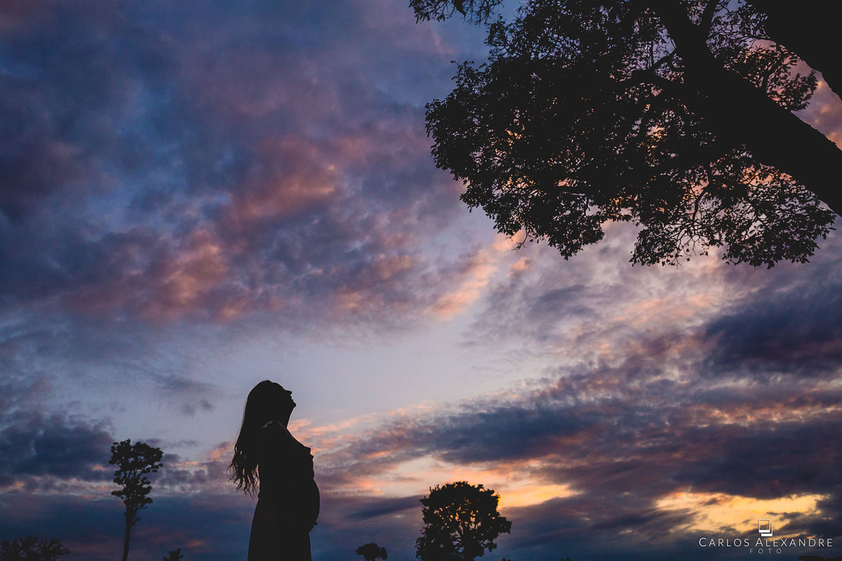 contraluz do fim de tarde com a mamãe de barrigão com os cabelos ao vento, no ensaio de gestante em três corações carlos alexandre foto
