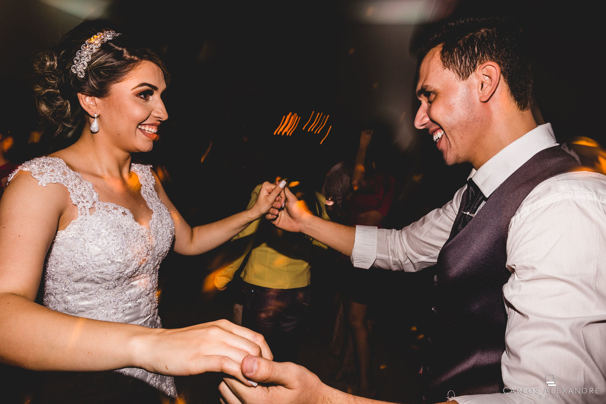 noivos dançam felizes da vida comemorando o seu casamento, fotógrafo de casamentos de três corações Carlos Alexandre Foto