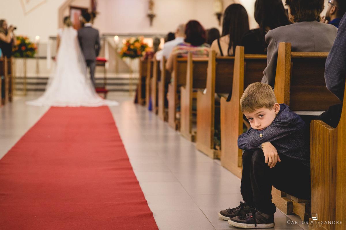 menino sentado com tédio esperando acabar o casamento para comer os docinhos