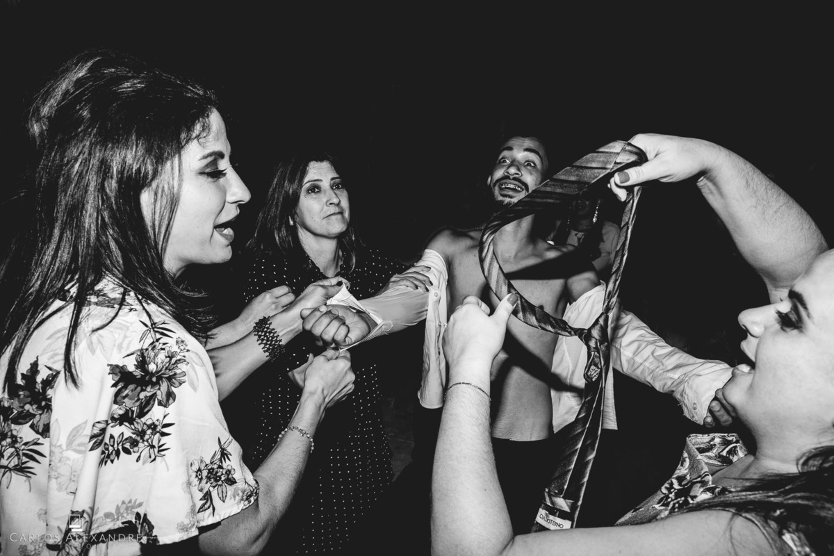 festa muito louca de casamento, com o convidado sem camisa sendo despido por mulheres, melhor fotógrafo de casamento carlos alexandre foto tres coraçoes mg
