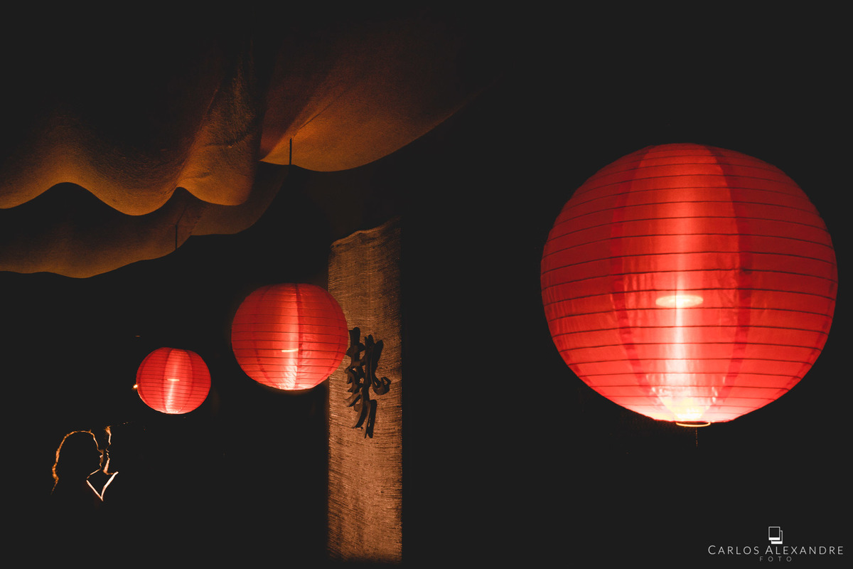 casal iluminados em um lindo ambiente de sushi, onde estão ao fundo em um contra luz, com balões japoneses guiando o olhar para eles, sessão de fotos em um sushi da bru tres corações MG sul de minas carlos alexandre foto