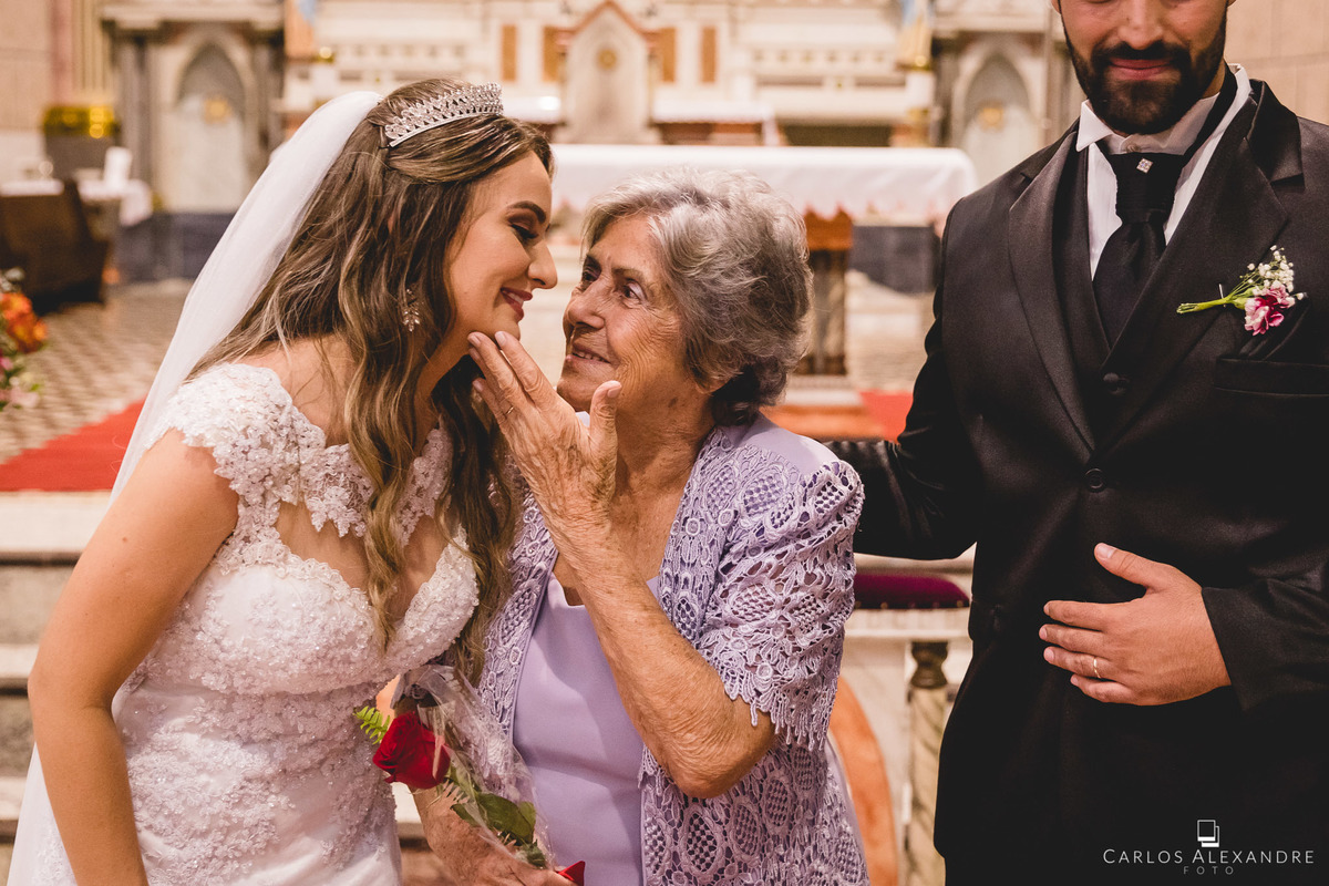 avó dando beijo na sua neta que acabou de se casar, casamento na igreja matriz sagrada família de três corações mg depois da reforma, fotos de casamentos carlos alexandre 