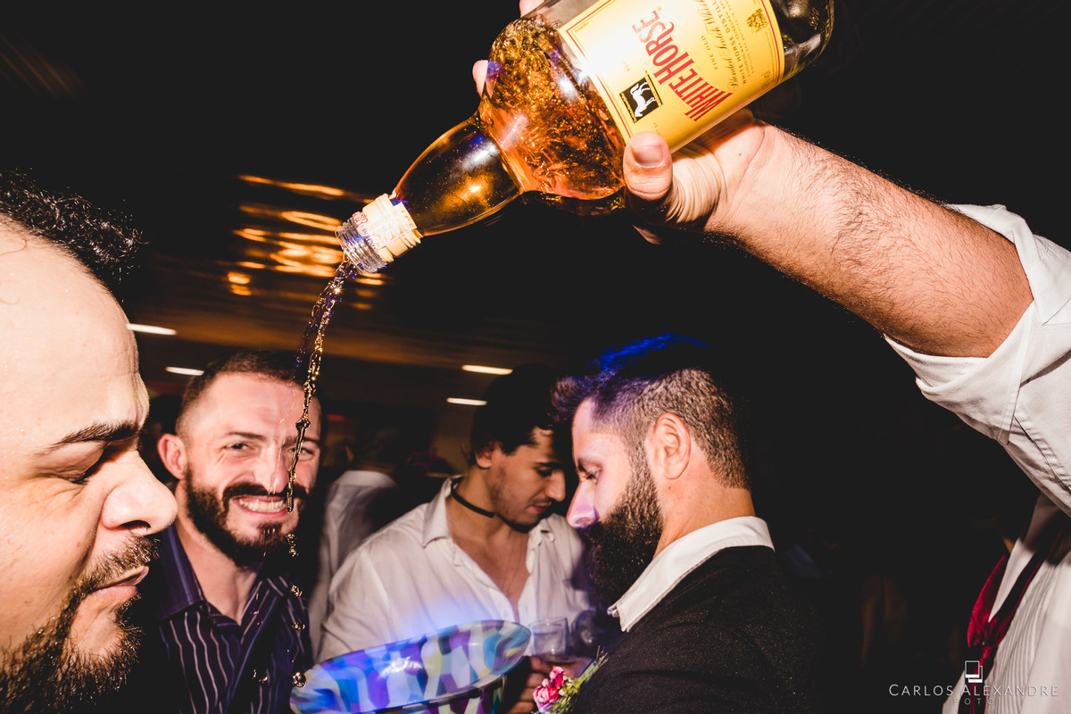 convidado bebendo whisky no bico da garrafa e derrubando um tanto para o santo, festa de casamento no círculo militar fotógrafo em três corações mg carlos alexandre