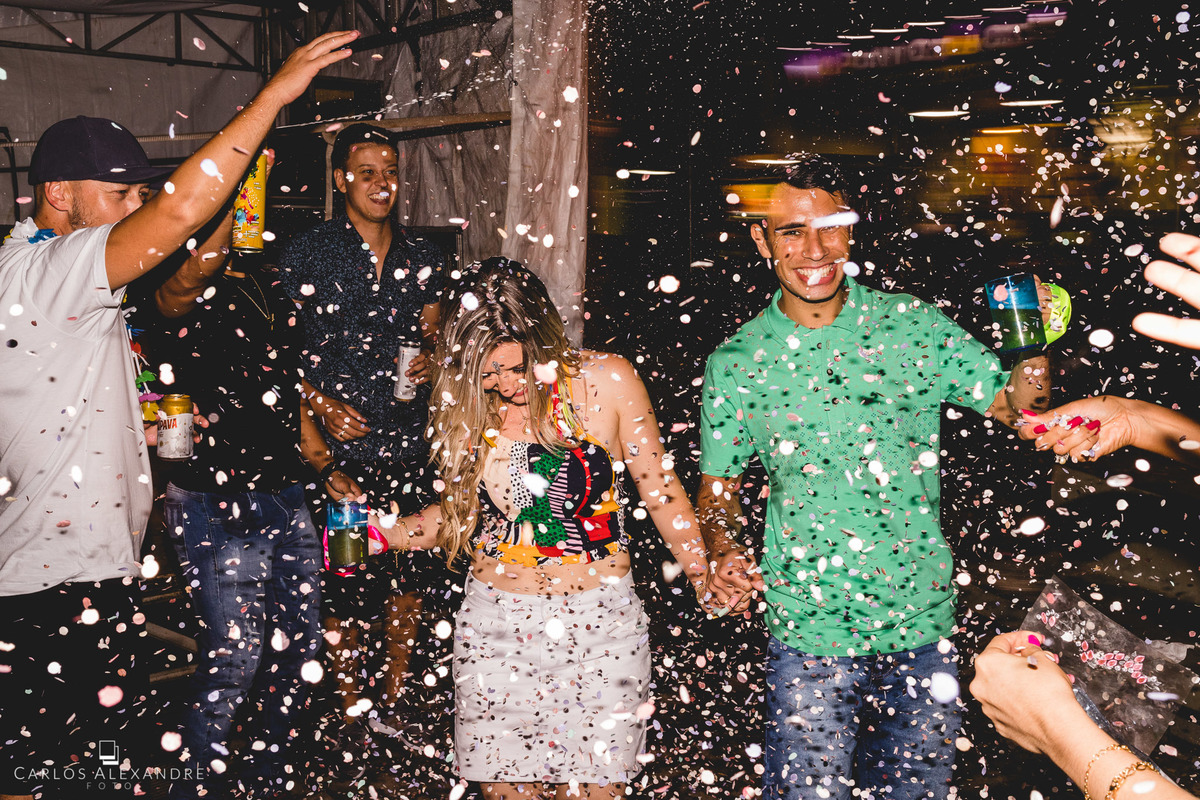 casal é recebido na roda da galera em meio ao carnaval com muito spray e confete no meio da bagunça, fotos de ensaio pré wedding no carnaval de lambari fotógrafo de casamento carlos alexandre foto em lambari três corações sul de mg 