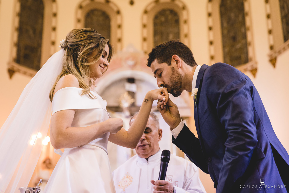 noivo beijando a mão de sua amada logo após colocar a aliança, na matriz catedral metropolitana de pouso alegre, fotógrafo de casamentos carlos alexandre de três corações mg sul de minas