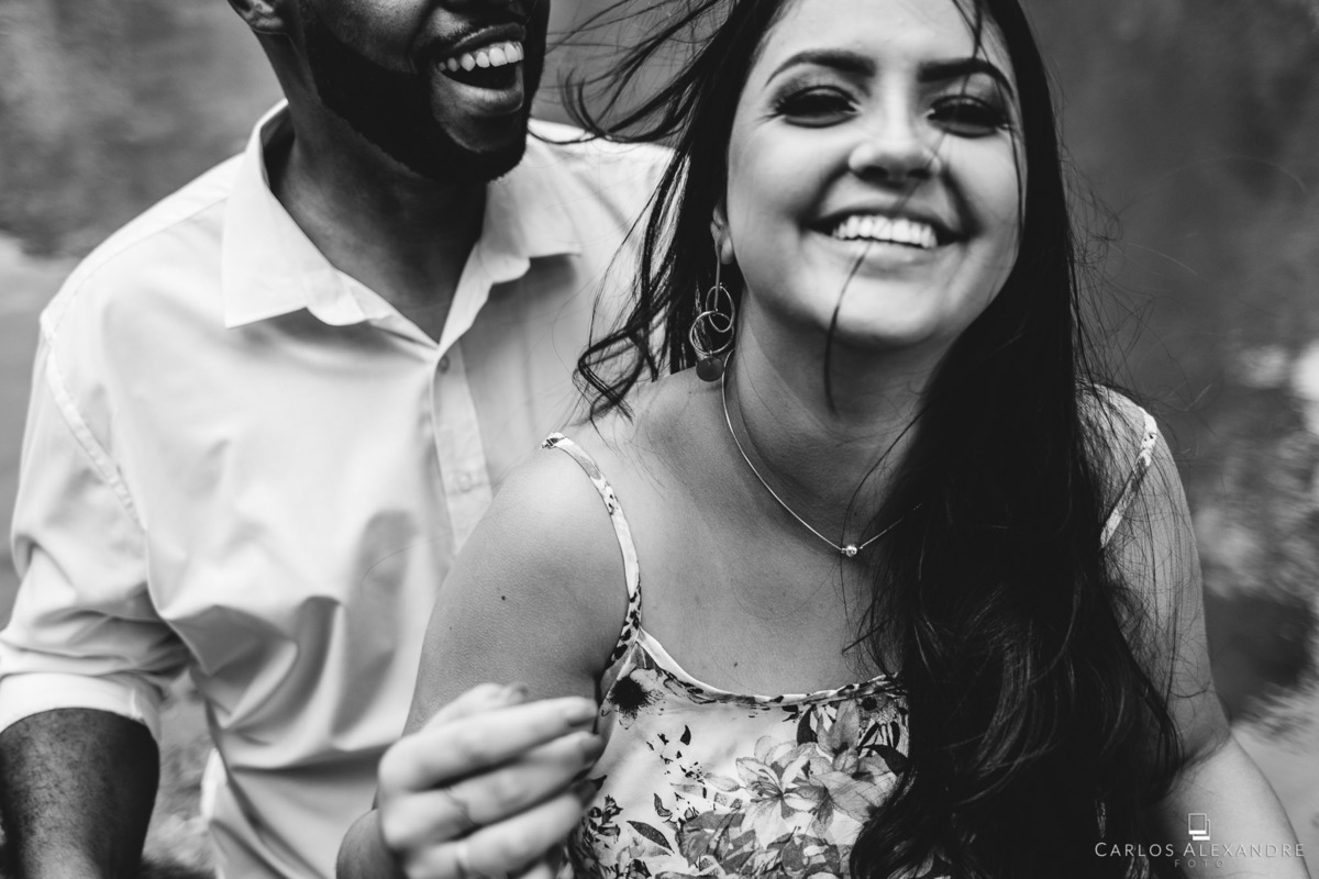 ensaio de casal  pré wedding na beira do rio no recanto da família em três corações mg carlos alexandre foto casal mais novo dando risada com os cabelos ao bento nessa foto em preto e branco