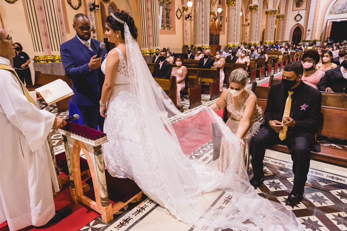 cerimônia de casamento na igreja matriz de três corações mg carlos alexandre fotógrafo mãe da noiva arrumando o seu vestido de Lia Noivas no momento em que ela vira de lado