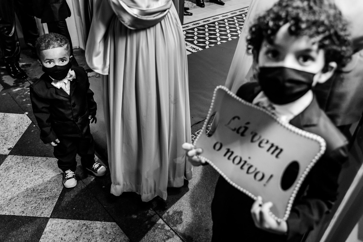 casamento na igreja matriz sagrada família em três corações mg fotografo de casamentos carlos alexandre foto pajens seguram plaquinha de lá vem o noivo