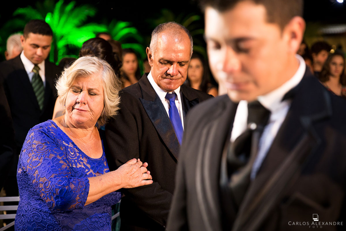 pais e sogros rezando durante o casamento do filho