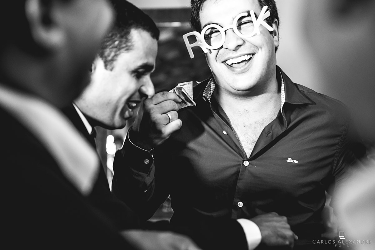 convidado feliz com óculos rock dando dinheiro pra lua de mel dos noivos