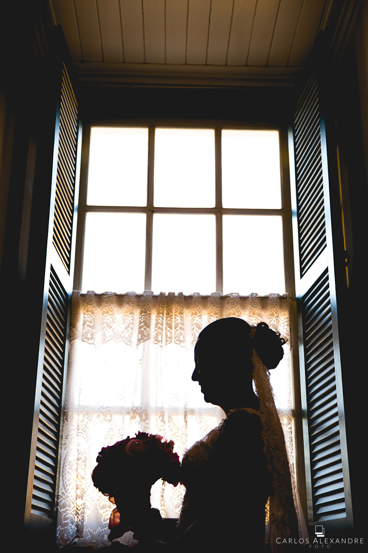 noiva de frente para a janela segurando o buque