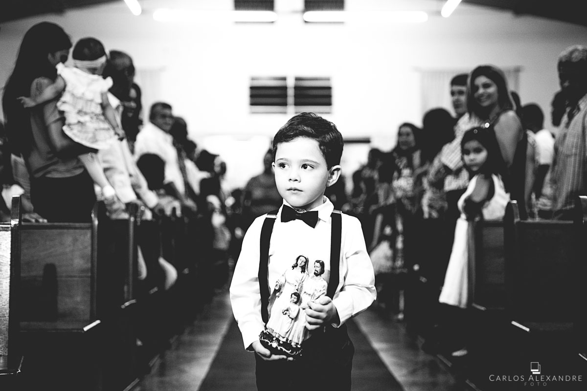 menino pajem entrando na igreja com uma imagem da sagrada família em mãos