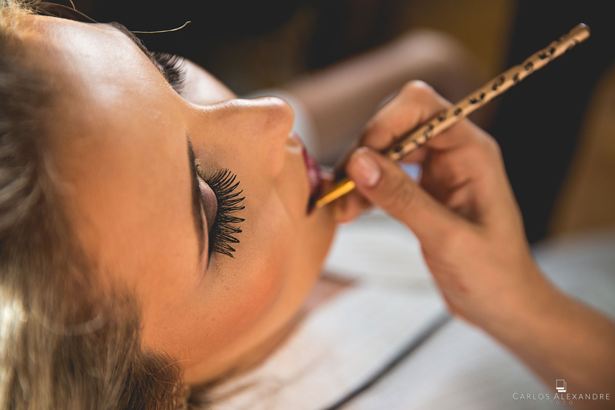 noiva finalizando os retoques e detalhes da maquiagem passando o batom
