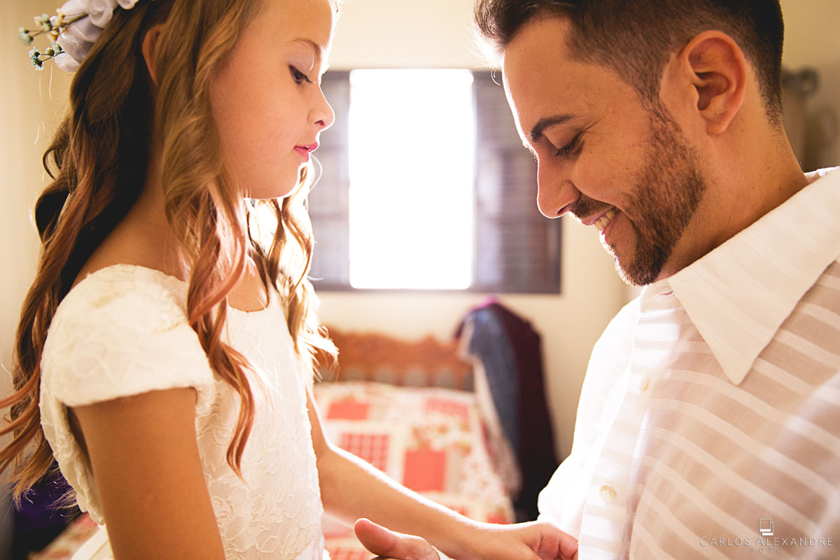 menininha arrumando e abotoando a camisa do pai para o casamento