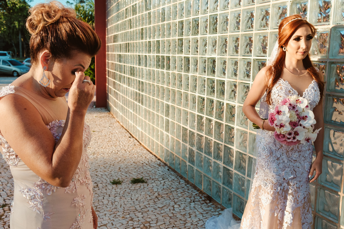 mãe emocionada ao ver a filha vestida de noiva esperando para entrar