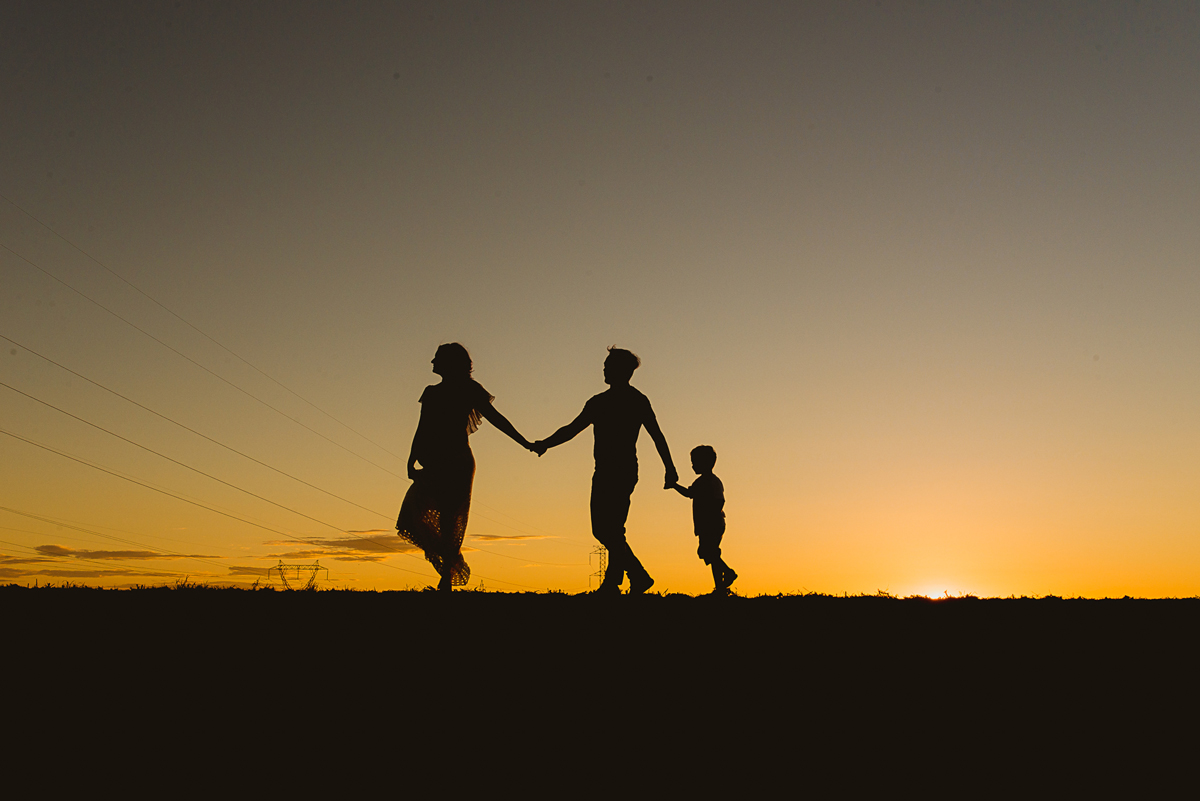 Silhueta da família caminhando junto no por-do-sol