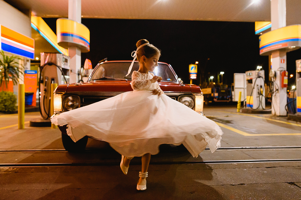 Filha dos noivos dançando na frente do carro, enquanto o carro abastece