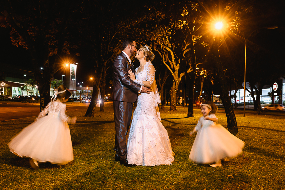 Foto feita em baixa velocidade com o casal parado e as filhas do casal rodando em volta deles