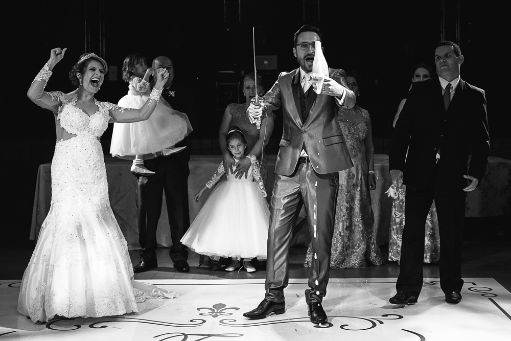 Noivo abrindo a garrafa do frisante com saibre